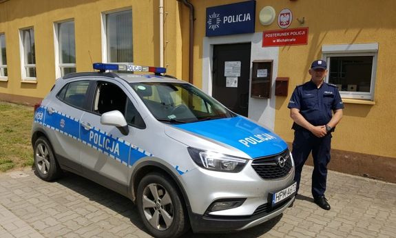 Policjant stoi przy radiowozie