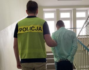 policjant prowadzi zatrzymanego mężczyznę