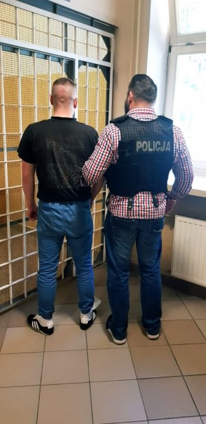 policjant prowadzi zatrzymanego