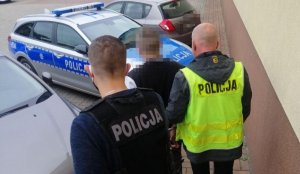 dwaj policjanci prowadzą zatrzymanego mężczyznę