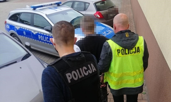 dwaj policjanci prowadzą zatrzymanego mężczyznę