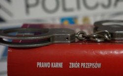 Książka: Prawo karne. Zbiór przepisów lezy na stole, a na nim kajdanki