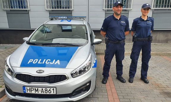 Dwóch policjantów stoi przy radiowozie