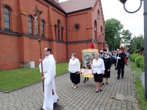 Ministrant z krzyżem za nim ludzie