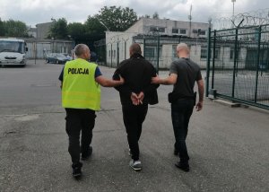 dwaj policjanci prowadzą zatrzymanego do aresztu