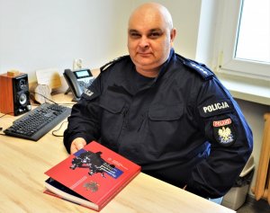 policjant trzyma książkę &quot;Granatowy porządek&quot;