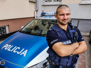 policjant stoi na tle radiowozu