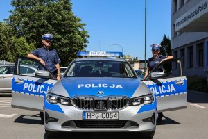 policjanci w mundurach przy radiowozie