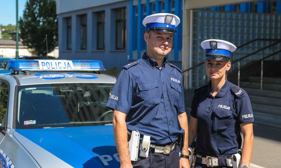 policjanci w mundurach przy radiowozie