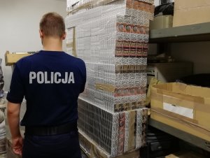 umundurowany policjant obok palety papierosów bez polskich znaków akcyzy