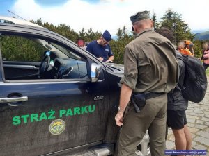 Strażnik Karkonoskiego Parku Narodowego oraz policjant przy samochodzie służbowym straży parku