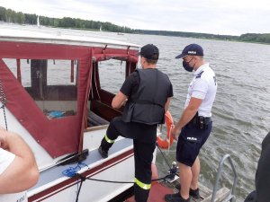 Policjant i strażak podczas kontroli łodzi&quot;&gt;