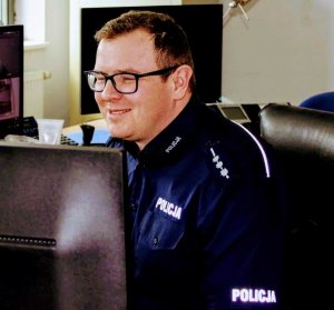 Policjant - dyżurny siedzący na stanowisku kierowania przed monitorem