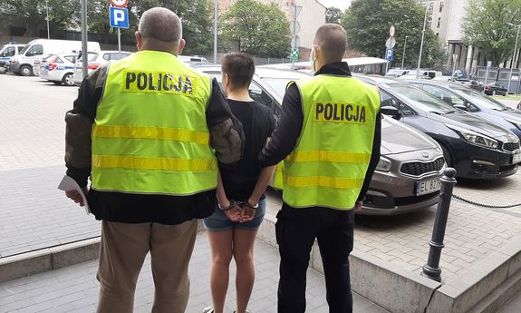 Policjanci prowadzą zatrzymaną kobietę