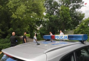 Radiowóz policyjny w tle policjanci z zatrzymanymi