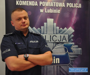 policjant w mundurze w tle napis: Komenda Powiatowa Policji w Lubinie
