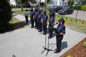 Policjantka przemawia przez mikrofon w tle stoją policjanci