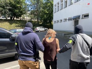 policjanci prowadzą zatrzymaną kobietę