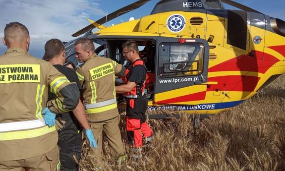 Śmigłowiec LPR obok stoją ratownicy medyczni i strażacy