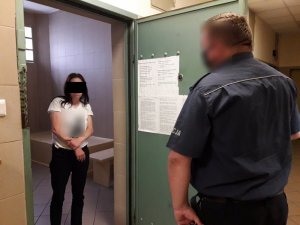 Policjant stoi obok zatrzymanej