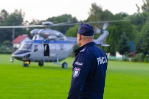 policjant na tle policyjnego helikoptera biorącego udział w poszukiwaniach&quot;&gt;