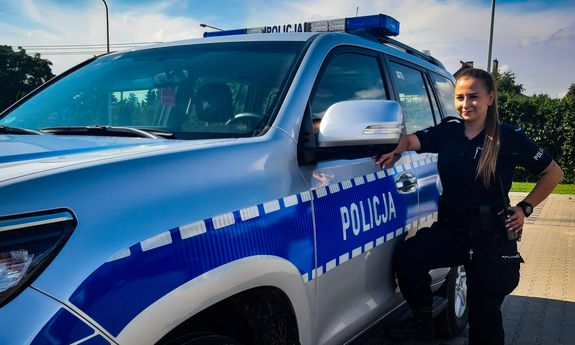 Umundurowana policjantka stoi obok radiowozu