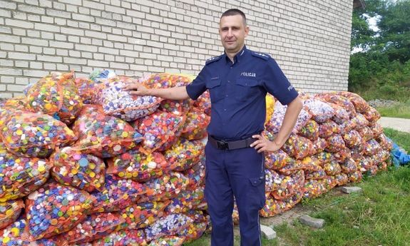 policjant w mundurze przy zebranych workach wypełnionych nakrętkami