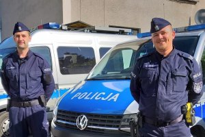 dwaj policjanci, w tle radiowozy policyjne