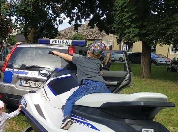mały chłopiec siedzący na policyjnym skuterze wodnym
