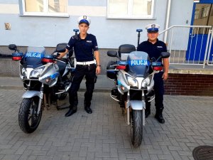 dwaj policjanci stoją przy motocyklach policyjnych
