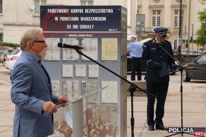 mężczyzna i policjant stoją przy mikrofonach w tle wystawa