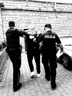 dwaj policjanci z zatrzymanym mężczyzną