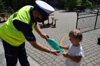 policjant przekazuje dziecku piłkę plażową