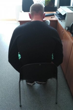 zatrzymany mężczyzna siedzi na krześle podczas przesłuchania