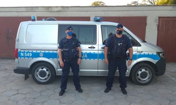 dwaj policjanci stoją obok radiowzu