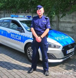 Policjant na tle radiowozu