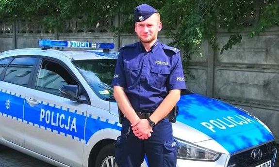 Policjant na tle radiowozu