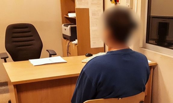 Na obrazku widzimy mężczyznę, który został zatrzymany przez policję, po tym jak na jednym z cmentarzy niszczył groby