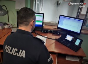 policjant dyżurny siedzi przy stanowisku i rozmawia przez telefon