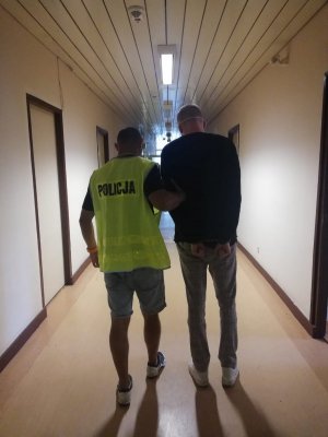 policjant prowadzi zatrzymanego mężczyznę