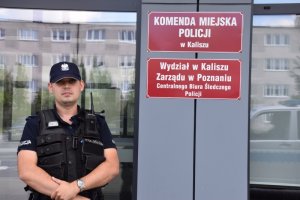 policjant stoi na tle budynku Komendy Miejskiej Policji w Kaliszu