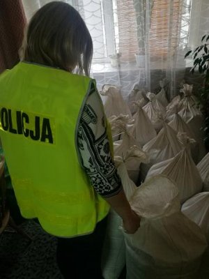 Zdjęcie przedstawia policjantkę w trakcie zabezpieczania worków z nielegalnym tytoniem.