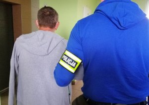 Policjant prowadzący zatrzymanego mężczyznę.