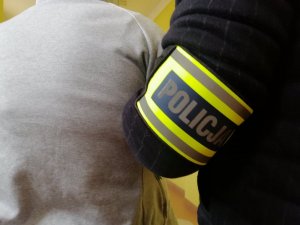 Policjant prowadzi poszukiwanego mężczyznę.