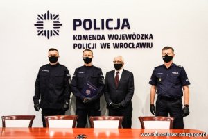 Na zdjęciu od lewej inspektor Maciej  Januszkiewicz - Komendant Miejski Policji we Wrocławiu, podkomisarz Dariusz Warecki z Wydziału Kadr Komendy Miejskiej Policji we Wrocławiu, Wojewoda Dolnośląski Jarosław Obremski i Komendant Wojewódzki Policji we Wrocławiu inspektor Dariusz Wesołowski w sali konferencyjnej Komendy Wojewódzkiej Policji  we Wrocławiu na ścianie w tle nowe logo Policji - gwiazda policyjna