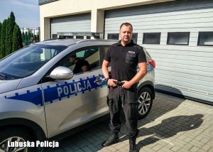 policjant stoi przy radiowozie&quot;&gt;