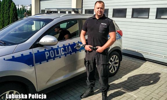 policjant stoi przy radiowozie&quot;&gt;