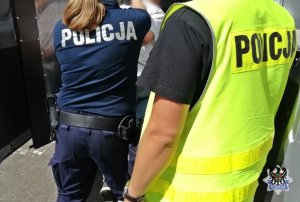 policjanci zamykają zatrzymaną osobę w radiowozie