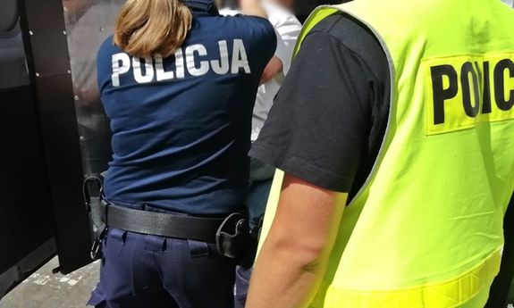 policjanci zamykają zatrzymaną osobę w radiowozie