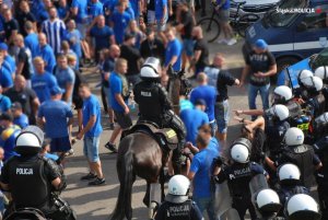 Zgromadzenie osób, nad porządkiem czuwa policja konna. Po prawej stronie widoczny radiowóz.&quot;&gt;